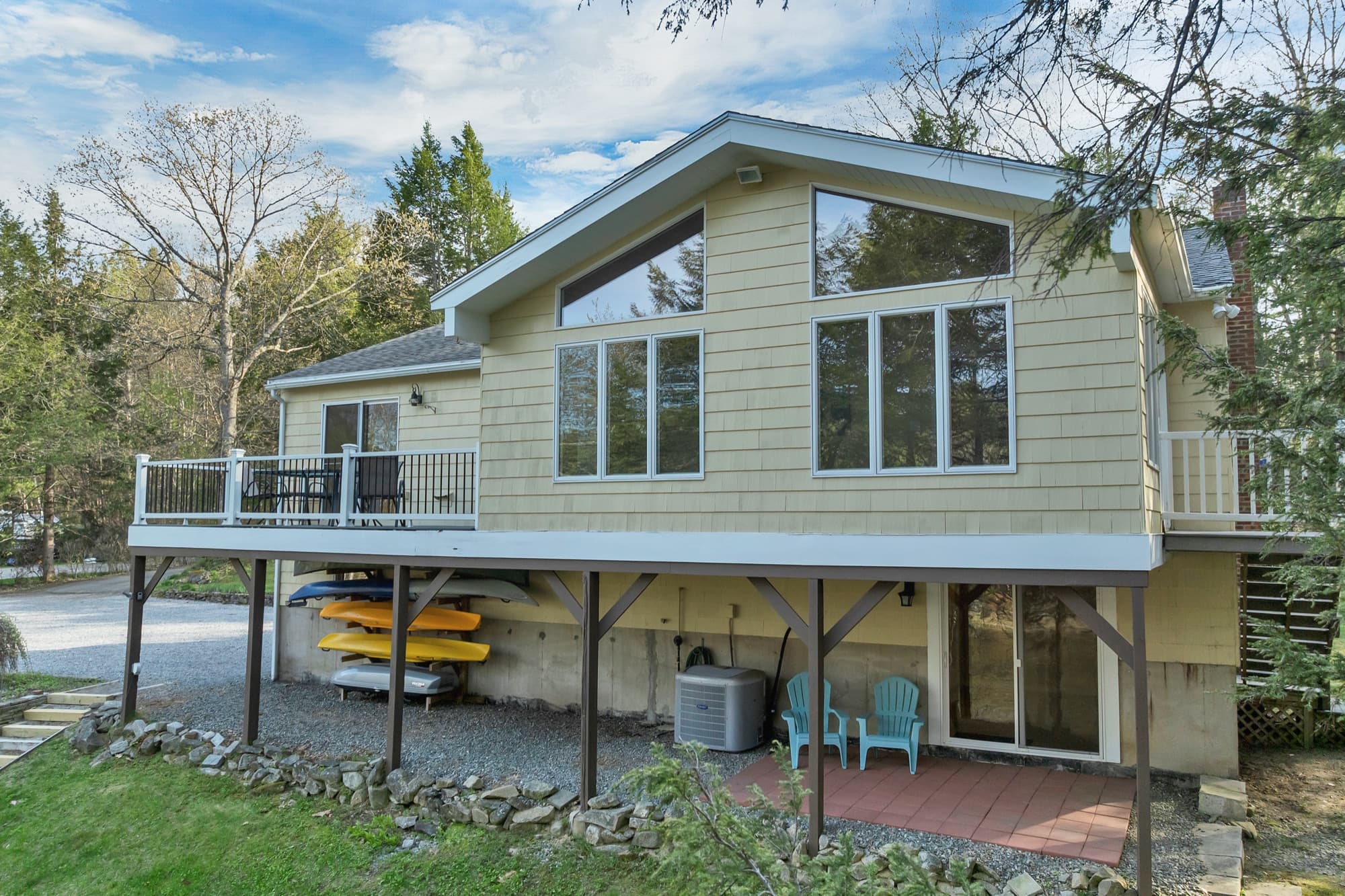 Rear of the house, with the composite deck, the tall window wall above, and kayaks stored underneath