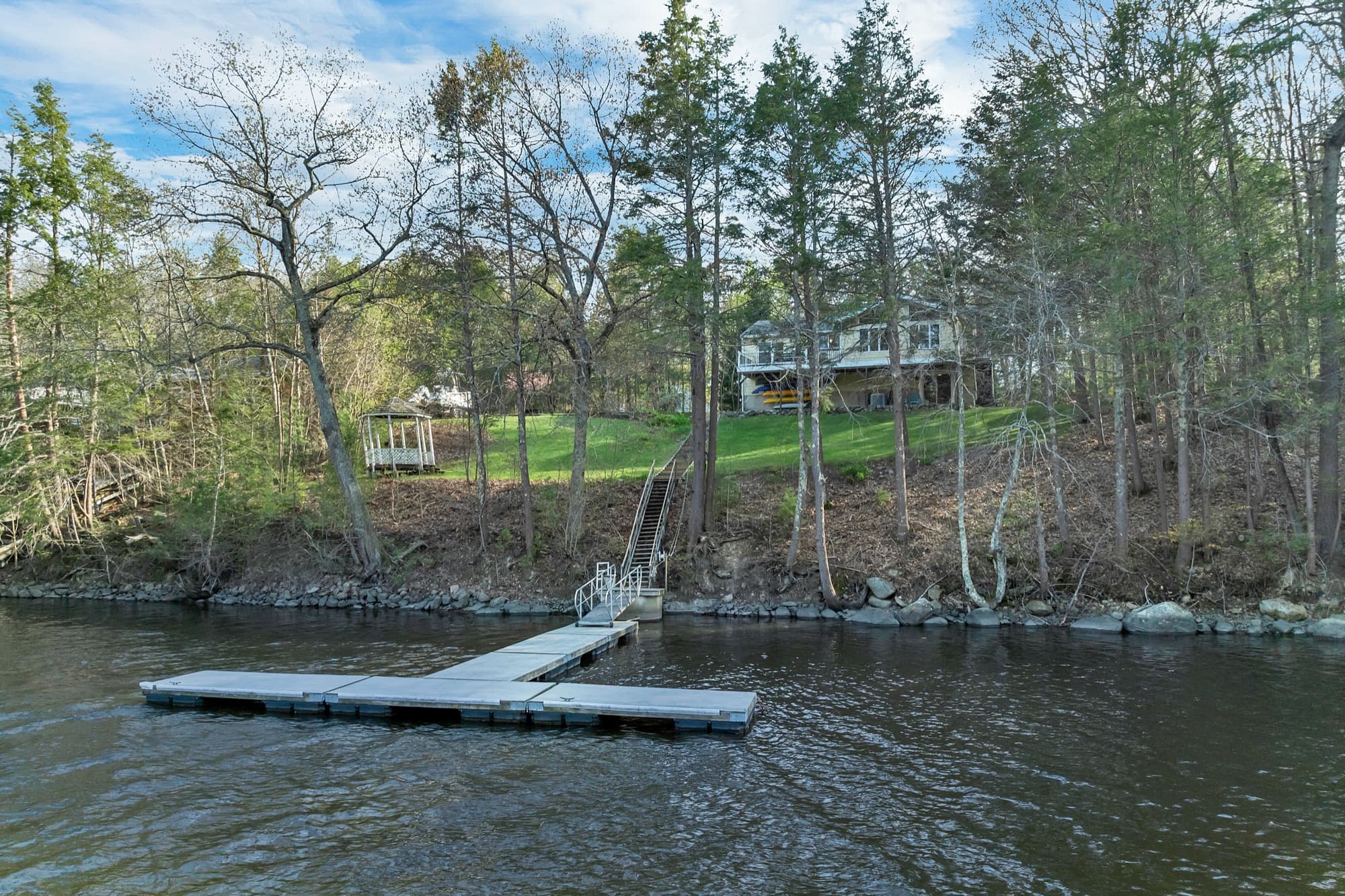 The property seen from the river, with the dock, lawn, gazebo, and house up the slope