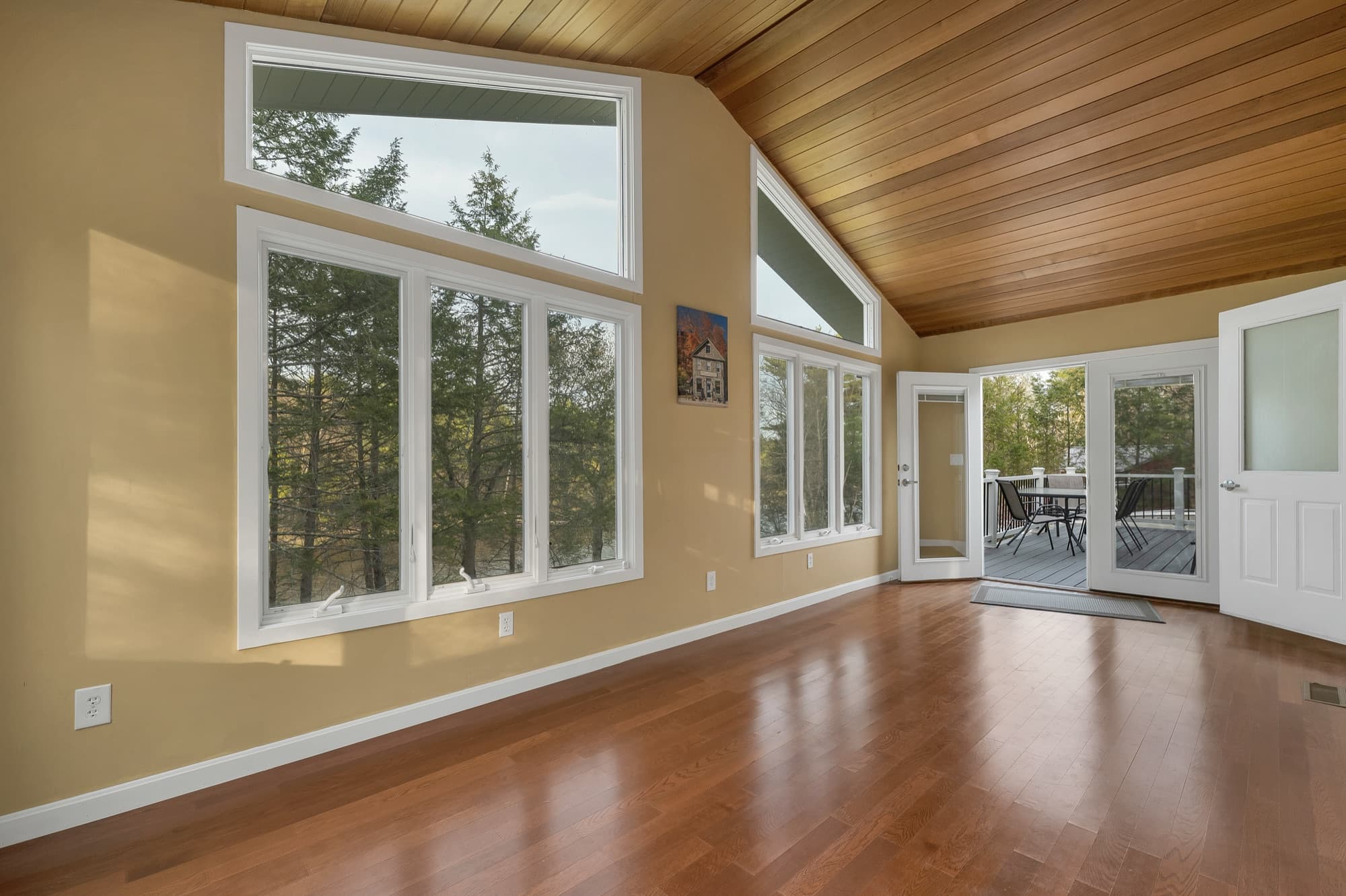 Screened porch under a wood cathedral ceiling, with a window wall and doors out to the deck