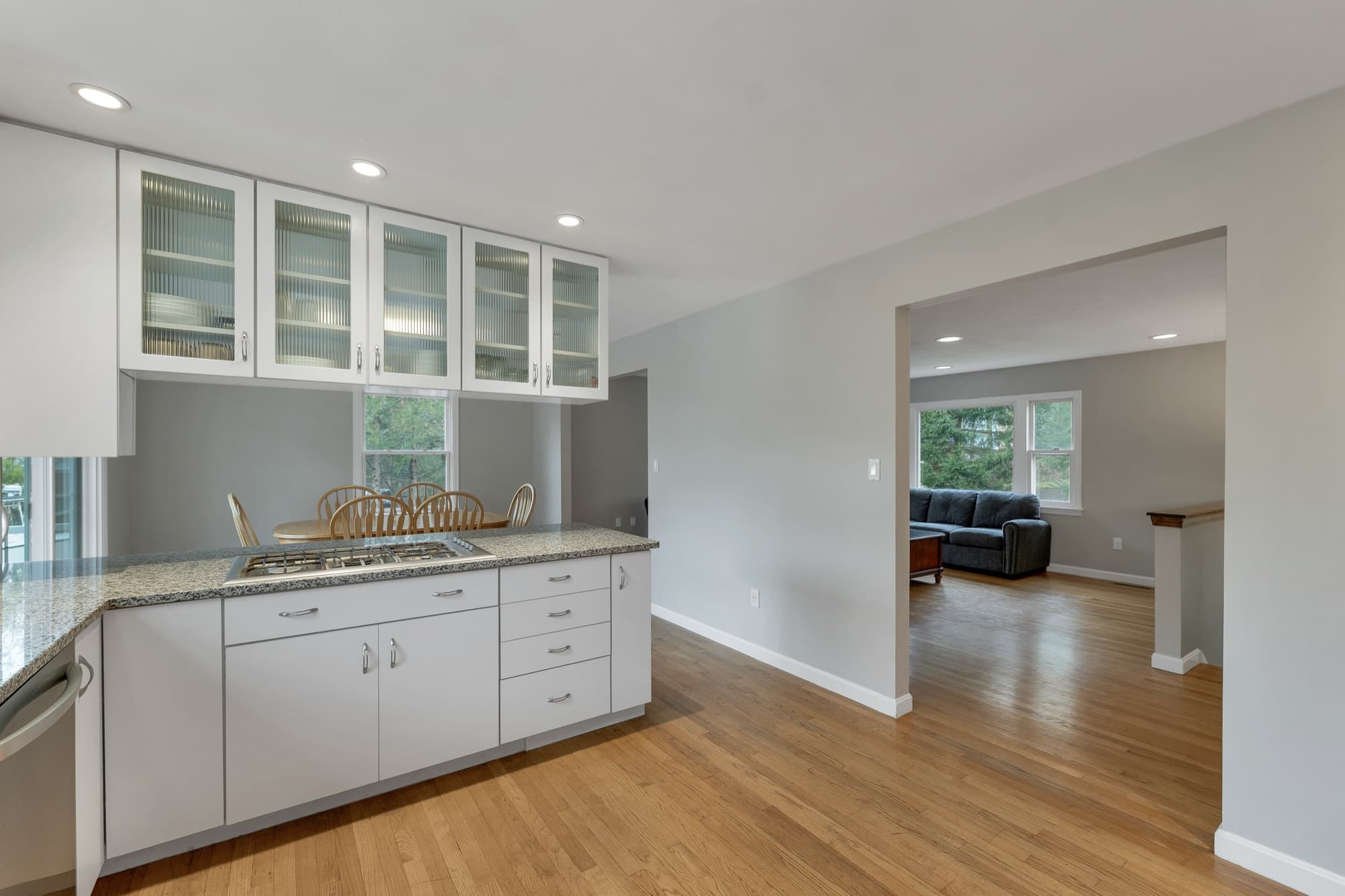 Kitchen with glass-front cabinets, opening through to the living room